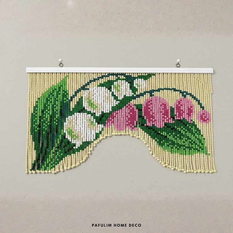 Puede incluir: Un tapiz de pared con cuentas que presenta un dise&ntilde;o floral de flores blancas y rosas con hojas verdes. La cortina de cuentas tiene un fondo color crema y est&aacute; montada en una barra blanca. El texto "PAFULIM HOME DECO" est&aacute; en la parte inferior.