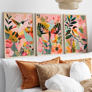 Könnte beinhalten: Ein Set aus drei gerahmten Wandbildern mit lebendigen botanischen und tierischen Illustrationen. Das linke Bild zeigt einen Kolibri, das mittlere einen großen Schmetterling und das rechte einen Vogel, jeweils vor einem rosafarbenen Hintergrund.