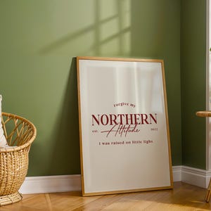 Framed typography print leaning against a green wall next to a woven basket and a plant on a light wood floor.