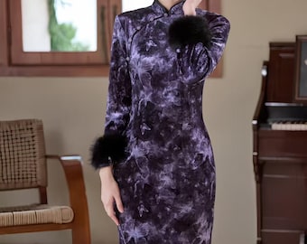 May include: A long, dark purple dress with a marbled pattern. The dress has long sleeves with black fur cuffs and a mandarin collar. The dress is a form-fitting style, and the model is standing in front of a window and a piano.