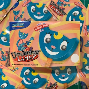 May include: Blue UmJammer Lammy ice pops with bubble gum eyes. The packaging features a cartoon cat playing a guitar. The ice pops are blueraspberry and lemon flavored.