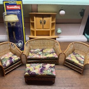 May include: A miniature wicker furniture set for a dollhouse, including a sofa, two chairs, an ottoman, and a small cabinet. The furniture is painted in a light brown color and features floral patterned cushions.