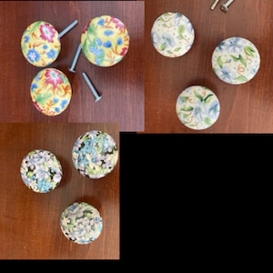 May include: Assortment of floral patterned cabinet knobs with silver screws. The knobs are in shades of blue, yellow, and white.