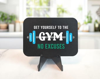 May include: Black chalkboard sign with a white stand. The sign says "Get yourself to the gym, no excuses." It features a gray barbell with blue weights on each side.