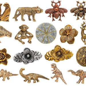 Op de afbeelding: Een verzameling decoratieve metalen knoppen en handgrepen in verschillende vormen, waaronder dieren, bloemen en geometrische ontwerpen. De knoppen hebben een reeks kleuren, waaronder goud, zilver en brons. De collectie bevat een cheetah, tijger, bij, paard, aap, bloem, hert en dinosaurus.