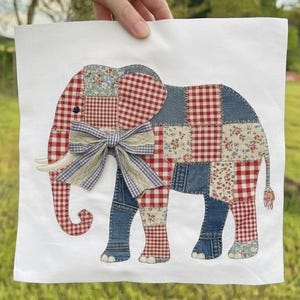 Puede incluir: Un tejido cuadrado blanco con un diseño de elefante de patchwork. El elefante está hecho de tela a cuadros rojos y blancos, mezclilla y estampados florales. Un lazo a rayas azules y blancas adorna el pecho. El elefante tiene colmillos de marfil y una pequeña cola.