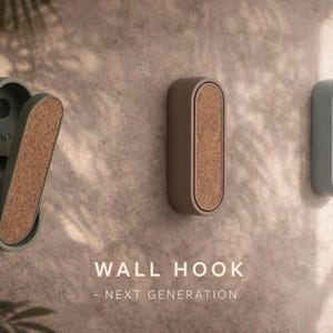 May include: Three wall hooks in shades of green, brown, and blue with cork inserts. One hook is open, revealing the interior. The text "WALL HOOK - NEXT GENERATION" is displayed below the hooks.