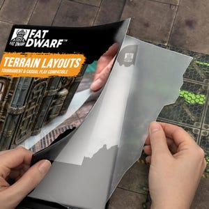 May include: A person is peeling back a clear plastic sheet from a Fat Dwarf Terrain Layouts product. The product packaging features the Fat Dwarf logo and the words "Terrain Layouts" in orange and white. The background shows a detailed terrain map.