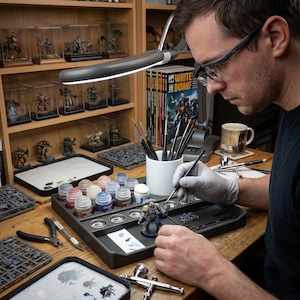 May include: A person painting a miniature figurine at a hobby station. The station includes paint bottles, brushes, and a lamp. Shelves display other figurines in clear cases. The book "White Dwarf" is visible in the background.