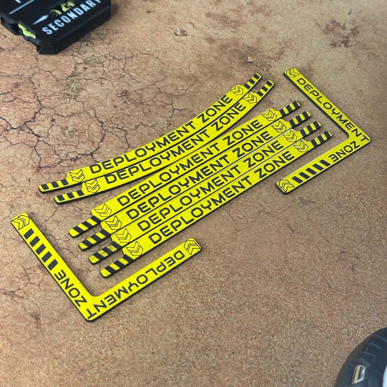 Warhammer 40k Deployment zone Guide in yellow with hazard markings, laid on a table showing the full contents of the set, 2Curved pieces, 4 straight pieces and 2 corner pieces