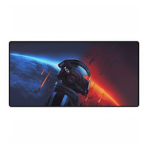 May include: A rectangular desk mat with a sci-fi design, showing a helmeted figure and the text "N7". The background features a planet and space with orange and blue colours. The mat has a black border.