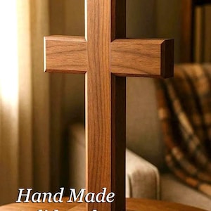 May include: A handcrafted wooden cross made of solid walnut. The cross is displayed on a table and features the text "Hand Made Solid Walnut". The cross has a simple, yet elegant design.