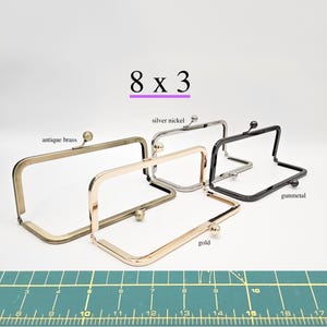 May include: Rectangular purse frames in antique brass, silver nickel, gold, and gunmetal finishes. The image shows the dimensions of the frames as 8 x 3 inches. Each frame has a ball clasp closure.