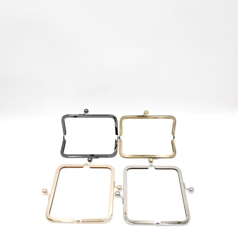 May include: Four metal purse frames in various finishes: black, gold, rose gold, and silver. Each frame has a rectangular shape with a clasp closure. The frames are shown against a white backdrop.