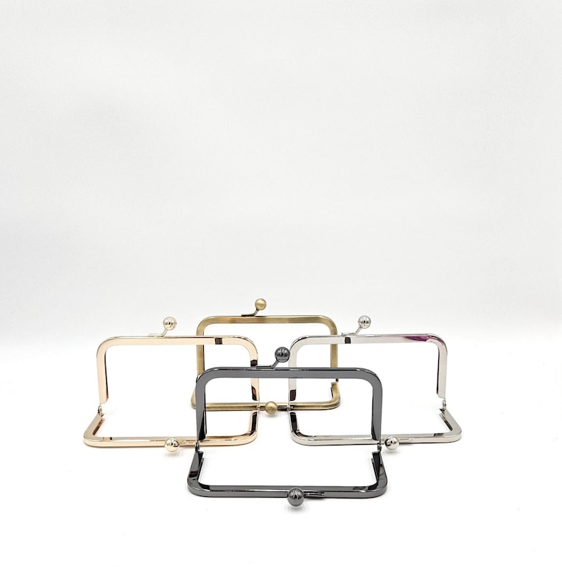 May include: Five metal purse frames in gold, silver, gunmetal, and brass. Each frame has a rectangular shape with a ball clasp closure. Ideal for crafting projects. Measurements are in centimetres.