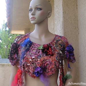 May include: A crocheted top featuring a colourful floral design. The top is crafted with a variety of textures and colours, including pink, purple, blue, and green. The top is adorned with flowers and leaves.