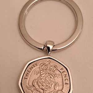 May include: Silver key ring with a 1982 twenty pence coin featuring a rose and crown. The coin is attached to a silver ring.