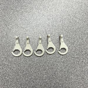 May include: Five white plastic hooks with a rounded shape. The hooks are designed for hanging items.