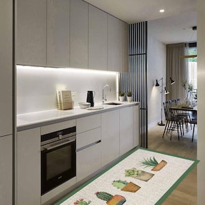 Può includere: Un tappeto da cucina rettangolare con uno sfondo testurizzato beige chiaro e un bordo verde. Il tappeto presenta un motivo ripetitivo di vari cactus verdi in vasi color marrone e terracotta, disposti in una sequenza lineare.