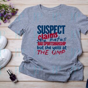 May include: Gray t-shirt with a blue and red graphic that says "SUSPECT claims she hates BAD SPORTSMANSHIP but she yells at THE UMP"