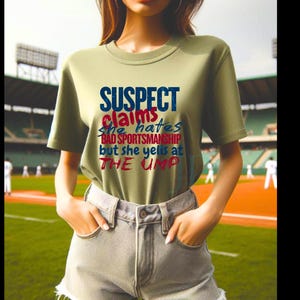 May include: A green t-shirt with the text "SUSPECT claims she hates BAD SPORTSMANSHIP but she yells at THE UMP" in blue, red, and white lettering.