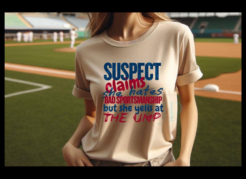 May include: A beige t-shirt with the text "SUSPECT claims she hates BAD SPORTSMANSHIP but she yells at THE UMP" in blue and red lettering.