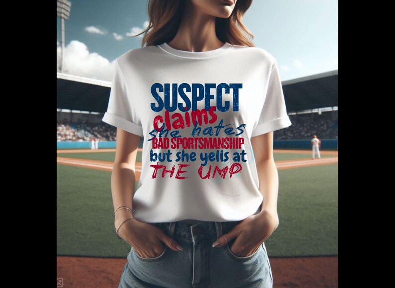 May include: White t-shirt with a blue and red graphic that says "SUSPECT claims she hates BAD SPORTSMANSHIP but she yells at THE UMP"