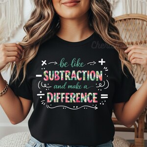 Peut inclure: T-shirt noir avec l'inscription "be like subtraction and make a difference" en blanc et imprimé floral. Le t-shirt comporte des symboles mathématiques et est porté par une personne.