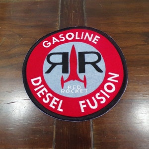 May include: A red, white, and black circular patch with the text "GASOLINE DIESEL FUSION" around the edge. In the center is a stylized rocket ship with the text "RED ROCKET" underneath.