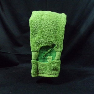 May include: A green hand towel with an embroidered green leaf design. The leaf is a stylized version of the iconic "leaf" from the popular video game Animal Crossing.