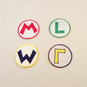 May include: Four embroidered patches with white backgrounds and colored letters. The patches are red with an 'M', green with an 'L', yellow with a 'Γ', and blue with a 'W'.