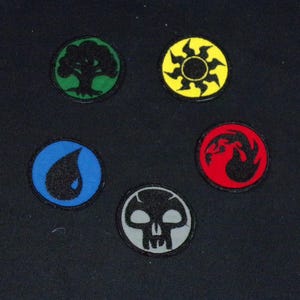 May include: Five circular patches with embroidered designs. The patches feature a tree, a sun, a water droplet, a skull, and a stylized flame. Each patch has a black border and is set against a dark background.