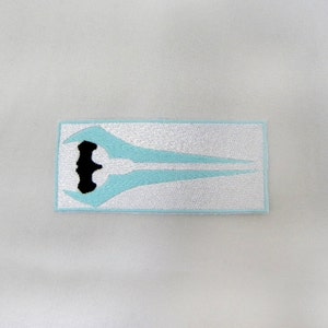 May include: A light blue embroidered patch with a black outline of a sword. The sword is a stylized design with a curved blade and a handle.