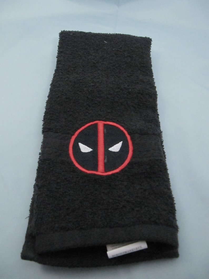 May include: Black hand towel with a red and white embroidered Deadpool logo.