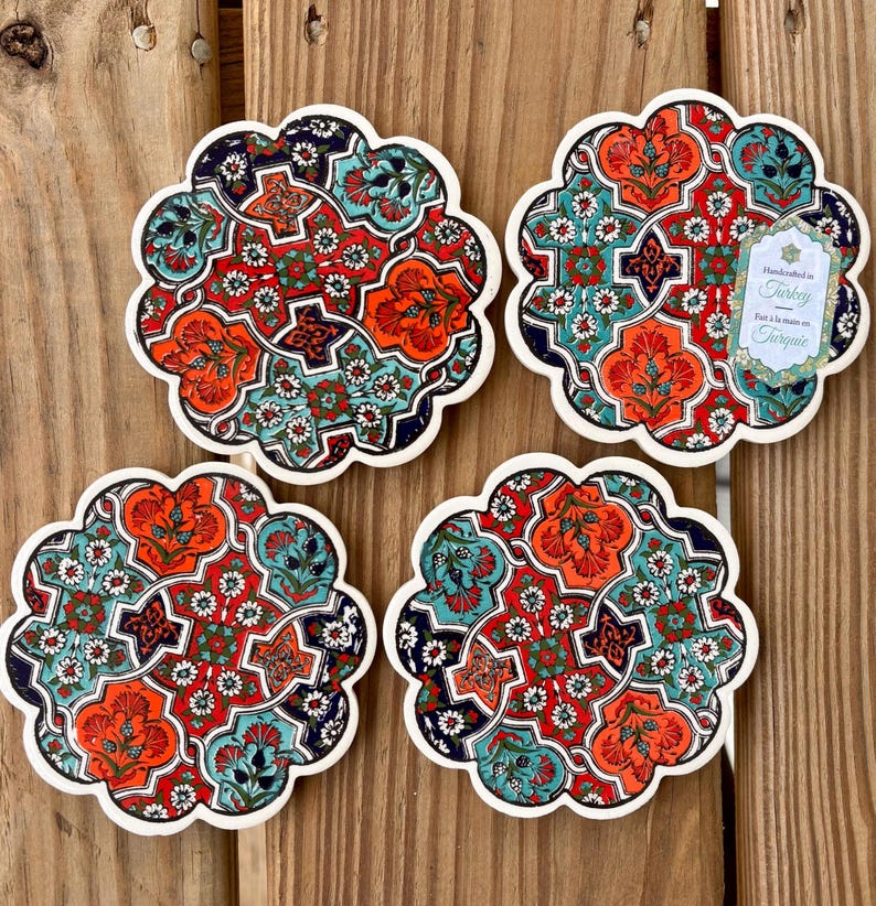 K&ouml;nnte beinhalten: Set aus vier Keramik-Untersetzern mit komplizierten floralen und geometrischen Mustern in Rot-, Blau-, Gr&uuml;n- und Wei&szlig;t&ouml;nen. Die Untersetzer sind handgefertigt in der T&uuml;rkei und tragen ein Etikett mit der Aufschrift "Handmade in Turkey, Fait &agrave; la main en Turquie".