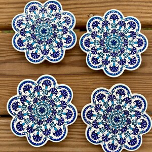 K&ouml;nnte beinhalten: Vier blaue und wei&szlig;e Keramik-Untersetzer mit einem Blumenmuster. Die Untersetzer sind blumenf&ouml;rmig mit 10 Bl&uuml;tenbl&auml;ttern.