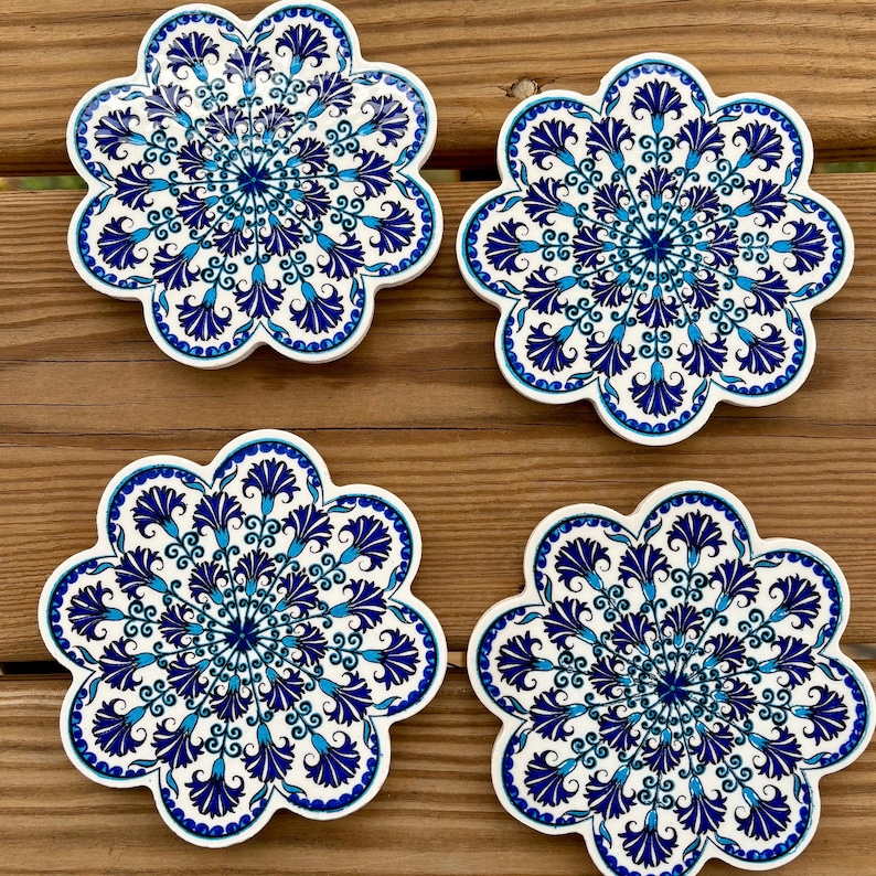 K&ouml;nnte beinhalten: Vier blaue und wei&szlig;e Keramik-Untersetzer mit einem Blumenmuster. Die Untersetzer sind blumenf&ouml;rmig mit 10 Bl&uuml;tenbl&auml;ttern.