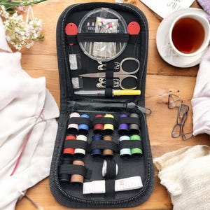 May include: A black zippered travel sewing kit with a variety of colorful threads, needles, pins, scissors, and a measuring tape. The kit is open and the contents are visible.
