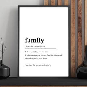 Könnte beinhalten: Schwarz gerahmter Druck mit der Definition von "Familie". Die Definition umfasst zwei Punkte: "Diejenigen, die dich am meisten lieben" und "Eine Gruppe von Menschen, die gezwungen sind, miteinander zu reden, wenn das WLAN ausfällt."