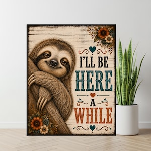 Op de afbeelding: Een rechthoekige wandkunstprint met een bruine luiaard die aan een boomtak hangt. De achtergrond heeft een lichte houtnerftextuur met bloemaccenten en de tekst "I'LL BE HERE A WHILE" in zwarte, blauwgroene en oranje letters.