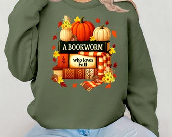 May include: Green sweatshirt featuring a fall-themed graphic. The design includes a stack of books, pumpkins, and autumn leaves. Text on the graphic reads "A Bookworm who loves Fall."