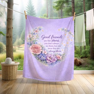May include: A lavender-colored blanket with a floral heart design. The heart is filled with pink, purple, and blue flowers. Text reads "Good friends are like stars, you don't always see them, but you know they are always there."
