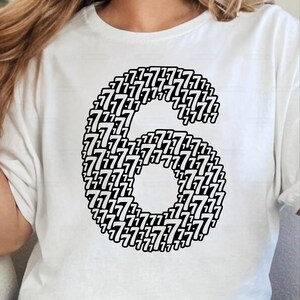 May include: White t-shirt featuring a large number six, composed of numerous smaller sevens in black. The design is centered on the shirt, creating a bold graphic statement. The shirt is made of a soft material.