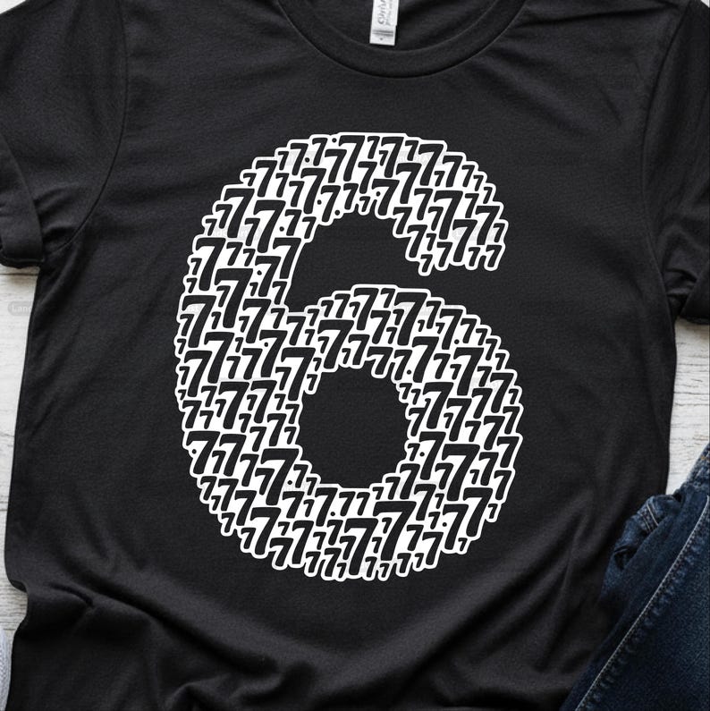 May include: Black t-shirt featuring a large white number six composed of smaller sevens. The design is centered on the shirt, with the number six taking up a significant portion of the front.