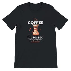 Op de afbeelding: Zwart T-shirt met een koffie-thema grafisch ontwerp. Het ontwerp toont de tekst "I'm Coffee" boven een illustratie van een koffiezetapparaat. Daaronder staat de tekst "Obsessed, I'm a java junkie, Coffee Team Forever."