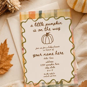 Peut inclure: Une carte d'invitation rectangulaire pour une fête prénatale avec une bordure à carreaux dans des tons orange, jaune et bleu. Le centre présente un cadre ondulé vert olive, une illustration de citrouille et le texte a little pumpkin is on the way.