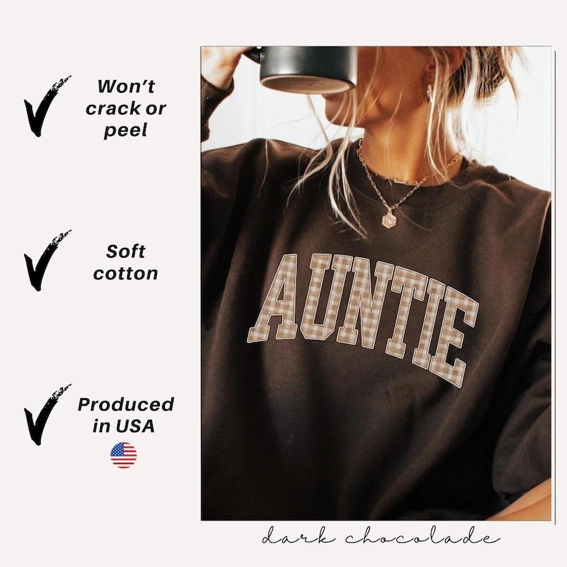 May include: Dark chocolate-colored sweatshirt with the word "AUNTIE" in a plaid design across the front. The sweatshirt is made of soft cotton and produced in the USA. The text "Won't crack or peel" is also visible.