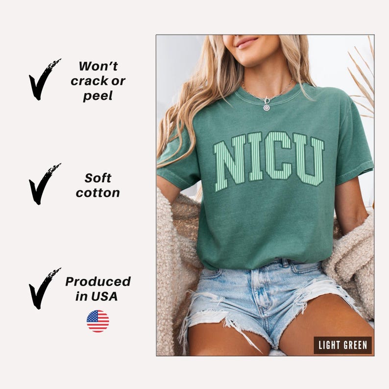 May include: A light green short-sleeve t-shirt featuring the text NICU in a varsity-style font with white vertical stripes. The shirt has a crew neckline and a relaxed fit. Text on the left lists features: Won't crack or peel, Soft cotton, Produced in USA.