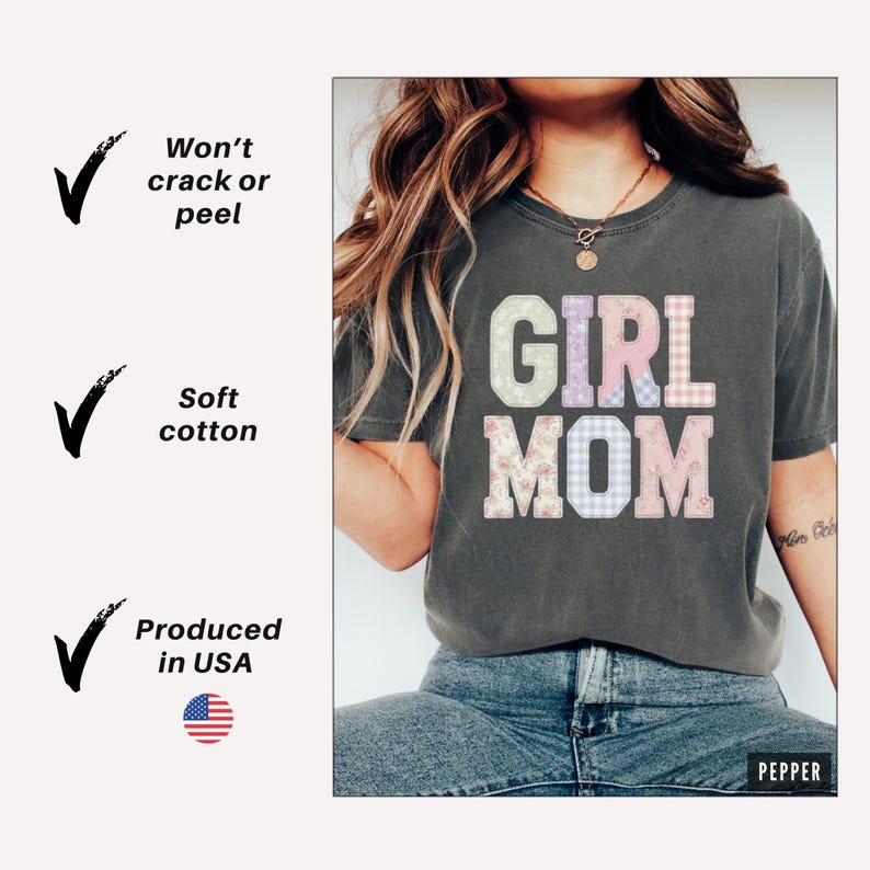 May include: Dark gray t-shirt with the words "GIRL MOM" in pastel colors and patterns. The shirt is made of soft cotton and is produced in the USA. The design won't crack or peel.
