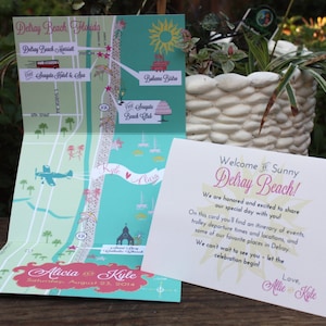 May include: A folded map with a hand-drawn illustration of Delray Beach, Florida, with a pink and green color scheme. The map highlights locations like the Seagate Beach Club, Bahamas Bistro, and Delray Beach Market. The map is accompanied by a white card with the text "Welcome to Sunny Delray Beach!" and a wedding announcement for Alicia and Kyle on August 23, 2014.